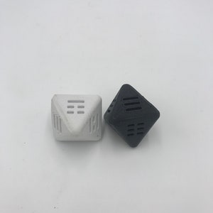 May include: Two geometric dice, one white and one black, with a unique design of lines and squares on each face.