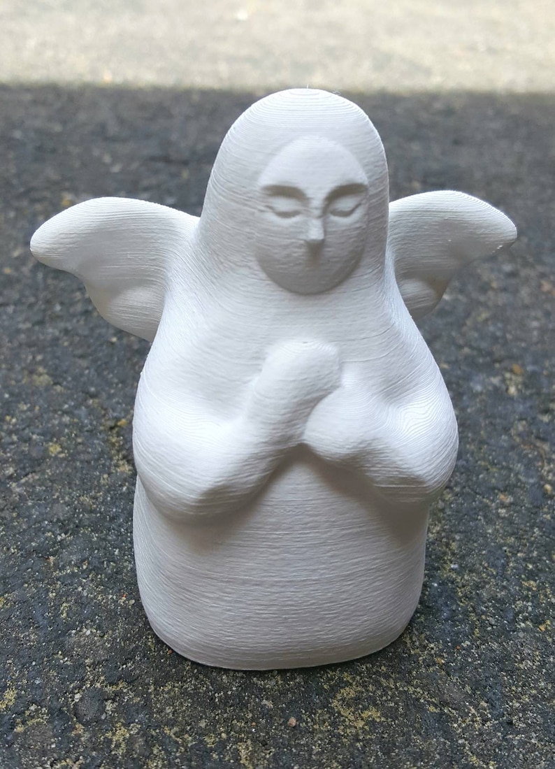 May include: White ceramic figurine of an angel with wings, closed eyes, and hands clasped in prayer.