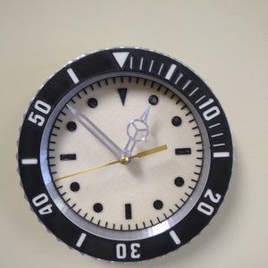 Puede incluir: Un reloj anal&oacute;gico blanco y negro con una esfera blanca y agujas negras. El reloj tiene un bisel negro con n&uacute;meros blancos alrededor del borde. Los n&uacute;meros son 10, 20, 30, 40 y 50.