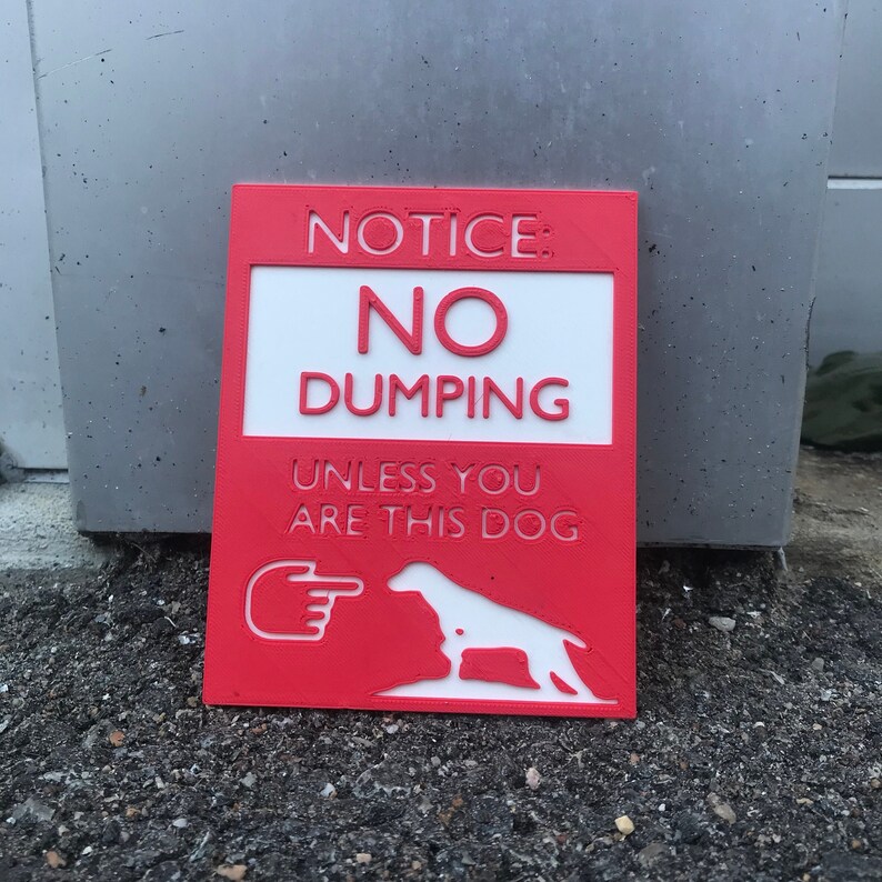 May include: Red sign with white text that reads "NOTICE: NO DUMPING UNLESS YOU ARE THIS DOG" with a white silhouette of a dog and a pointing hand.