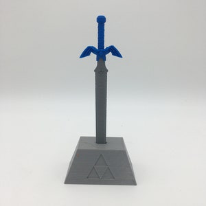 May include: A blue and gray 3D printed Master Sword replica with a stand featuring the Triforce symbol.