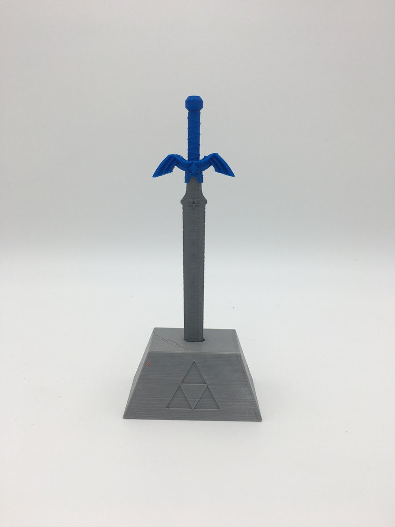 May include: A blue and gray 3D printed Master Sword replica with a stand featuring the Triforce symbol.