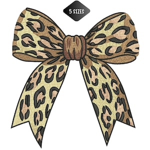 Puede incluir: Un lazo bordado con un estampado de leopardo en beige, marrón y negro. El lazo presenta un nudo central y extremos fluidos. Una etiqueta negra en forma de diamante sobre el lazo dice "5 SIZES".