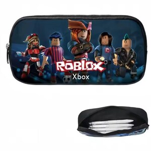 Puede incluir: Estuche negro con un gr&aacute;fico colorido de personajes de Roblox. El texto "ROBLOX for Xbox" est&aacute; en la parte delantera. El estuche tiene cremallera e incluye una imagen m&aacute;s peque&ntilde;a del estuche abierto con bol&iacute;grafos.