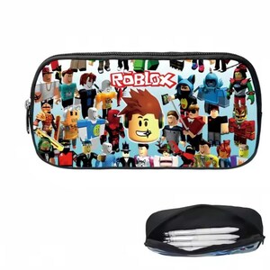 Puede incluir: Estuche negro con un dise&ntilde;o colorido con varios personajes de Roblox y el logotipo de Roblox. El estuche tiene cierre de cremallera e interior negro. Debajo se ve un segundo estuche abierto con bol&iacute;grafos.