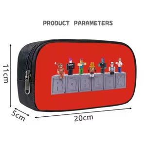 Puede incluir: Estuche negro con un dise&ntilde;o rojo que presenta varias figuras peque&ntilde;as y la palabra "ROBLOX". El estuche mide 20 cm de largo, 11 cm de alto y 5 cm de ancho.