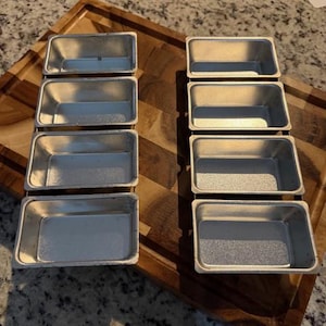 May include: A set of three ceramic mugs with a speckled, matte finish. The mugs are in shades of cream, light gray, and dark gray. Each mug has a simple, minimalist design, perfect for coffee or tea.