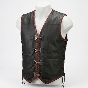 May include: Black leather vest with red stitching around the edges and along the seams. The vest has a V-neck and features three metal clasps down the front. Side laces and a small pocket add detail to this garment.