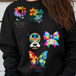 May include: Black sweatshirt with colorful graphics related to autism awareness. Designs include a sunflower, puzzle pieces, a smiley face, a bow, and a butterfly. Text includes "We Need Each Other," "Autism Acceptance Always," and "Spread Love Not Awareness."