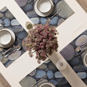 May include: Overhead shot of a table setting with four place settings. Each setting includes a white plate, bowl, silverware, and a placemat with a stone design. A centerpiece of purple flowers sits in the middle.