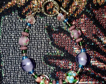 Pulsera de estilo antiguo con estampado floral en tonos morado, turquesa y verde.