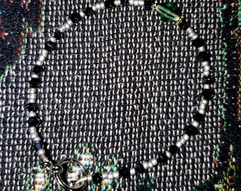 Pulsera sencilla de lunares negros con un centro de color verde azulado intenso.