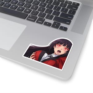 May include: A sticker featuring an anime-style illustration of a character with long black hair and red eyes. The character is wearing a red jacket over a white shirt and black tie. The sticker is placed on a laptop.