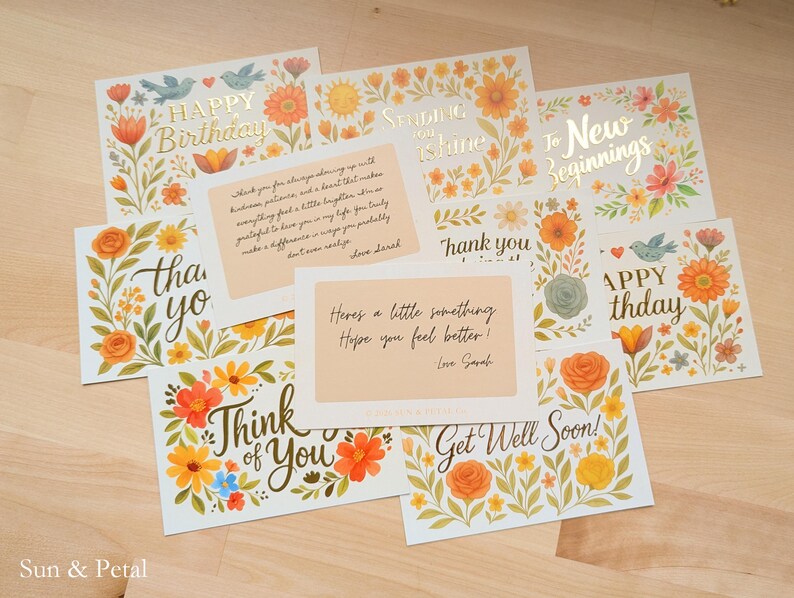May include: A collection of rectangular greeting cards featuring floral illustrations in orange, yellow, and green. The cards display various messages including Happy Birthday, Sending You Shine, To New Beginnings, Thank You, Think of You, and Get Well Soon.
