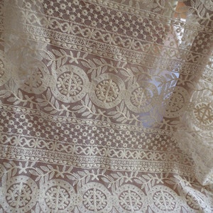 Puede incluir: Tela de encaje blanca con un delicado patr&oacute;n floral. El encaje tiene un dise&ntilde;o repetitivo de peque&ntilde;as flores y hojas, creando un aspecto delicado y femenino.
