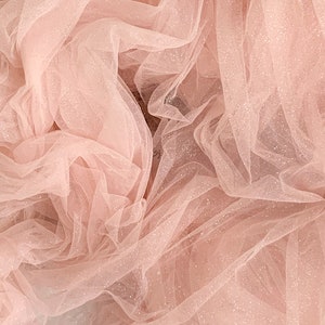 May include: Pink tulle fabric with a sparkly finish. The fabric is soft and delicate, and it has a subtle shimmer.