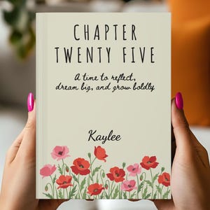 May include: A book cover with the title "CHAPTER TWENTY FIVE" in black text. Below the title is the phrase "A time to reflect, dream big, and grow boldly." The author's name, "Kaylee," is below the quote. The cover features red and pink floral illustrations.