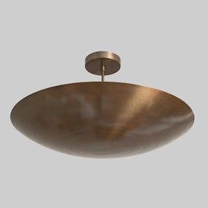 Peut inclure: Un plafonnier en forme de bol de couleur bronze. Le luminaire présente un design de bol large et peu profond et une petite plaque de montage circulaire. La lumière est suspendue à une courte tige, créant une esthétique minimaliste et moderne.