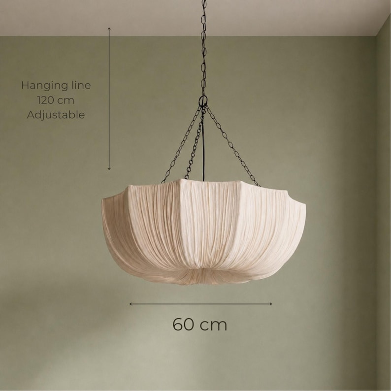 May include: A cream-colored, pleated fabric pendant light fixture with a scalloped edge. It hangs from a dark metal chain and features an adjustable hanging line of 120 cm and a diameter of 60 cm, as indicated by the text in the image.