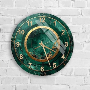 May include: Circular wall clock with a green marble effect and gold detailing. The clock face has gold numerals and hands, set against a dark green backdrop. The clock is mounted on a white brick wall.