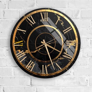 Puede incluir: Un reloj de pared redondo con esfera de mármol negro y números romanos dorados. El reloj tiene detalles y manecillas doradas y está montado en una pared de ladrillo blanco. El diámetro del reloj es de unos 30 cm.