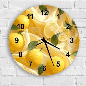 May include: A round wall clock featuring a vibrant yellow lemon and green leaf pattern printed over a soft, draped fabric background. The clock face displays bold black numbers from 1 to 12 and three black hands indicating the time.