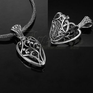 May include: A silver pendant with an ornate, openwork design. The pendant is shaped like a stylized teardrop with intricate scrollwork and a bail for a chain. The image also shows a close-up of the pendant's back, and a silver chain.