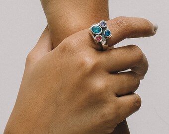 Anillo único con piedras semipreciosas. Anillo con piedras de nacimiento de amatista, topacio, peridoto, perla y granate.