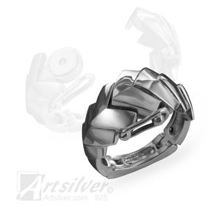 Puede incluir: Un anillo geométrico de plata con cierre de bisagra. El anillo está hecho de triángulos entrelazados y tiene un acabado pulido.