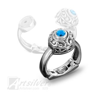 May include: A silver ring with a blue gemstone set in a filigree design. The ring has a hinged opening and is made of 925 sterling silver.