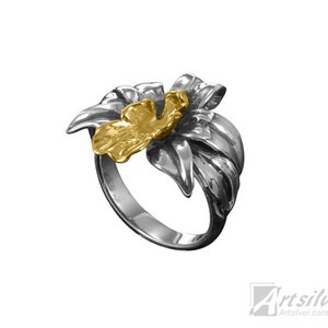 May include: A silver ring with a gold flower design. The flower has a textured surface and is set on a silver band.