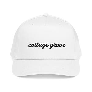 Puede incluir: Gorra de béisbol blanca con visera curva. El texto "cottage grove" está bordado en negro en cursiva en la parte delantera. La gorra tiene un ajuste estructurado y un botón en la parte superior.