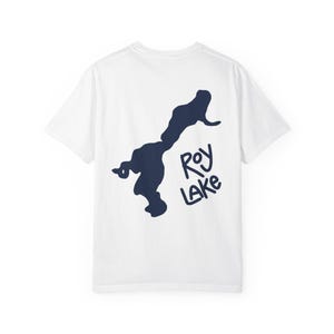 Puede incluir: Camiseta blanca con un gráfico azul marino de un lago y las palabras "Roy Lake" en un estilo manuscrito. El gráfico está en la parte posterior de la camiseta. La camiseta tiene mangas cortas y cuello redondo.