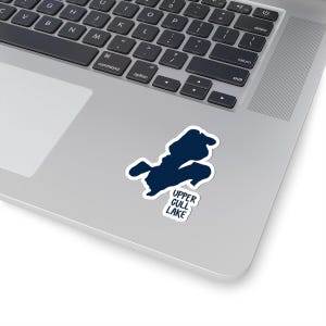 Puede incluir: Una pegatina azul marino con el contorno del lago Upper Gull, con el nombre del lago en texto blanco. La pegatina está colocada en un portátil plateado.