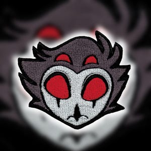 Pode incluir: Patch bordado com um personagem estilizado semelhante a uma coruja com um rosto branco, olhos vermelhos grandes e penas cinzentas. O patch tem uma borda preta e é para roupas ou acessórios.