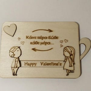 May include: A light-colored wooden plaque with a handle, featuring engraved cartoon figures of a boy and a girl facing each other. The plaque includes a heart, arrows, and the text "Happy Valentine's".