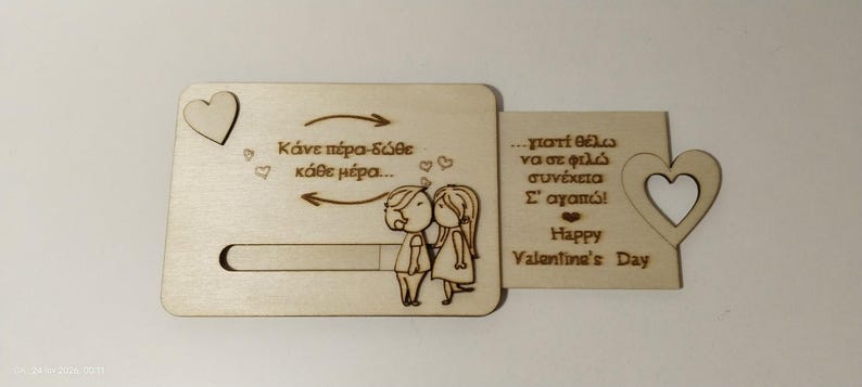 May include: A wooden Valentine's Day card with a sliding mechanism. The card features engraved text and illustrations of a couple, hearts, and arrows. The text includes "Happy Valentine's Day".