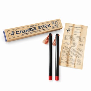 May include: A vintage "Royal Chinese Stick" magic set. The set includes two black sticks with red tips and tassels, a cardboard box, and instructions. The box reads "Royal Chinese Stick" and "The Famous Stage Effect in Pocket Size."