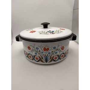 May include: White enamel cooking pot with a black rim, handles, and lid. The pot is decorated with a floral pattern in red, blue, and brown. The lid has a black knob.