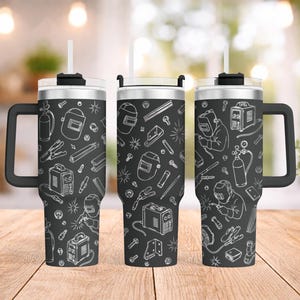 May include: Three black insulated travel mugs featuring a white line drawing of welding tools and equipment. Each mug has a black handle, a clear lid, and a white straw. The design includes welding helmets and other tools.