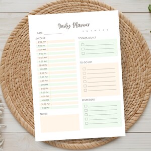 May include: A white daily planner sheet featuring the text Daily Planner at the top, a date line, and a schedule from 6:00 AM to 11:00 PM with alternating peach and light green rows, plus sections for goals, a to-do list, reminders, and notes.