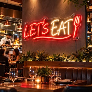 Peut inclure: Une enseigne néon murale affichant le texte "LET'S EAT" en lumière rouge vive et blanc chaud, accompagnée d'une icône de fourchette en néon rouge. L'enseigne est fixée sur un mur gris foncé texturé au-dessus d'une banquette en bois.