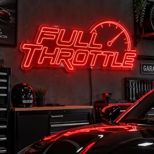 May include: A bright red neon sign mounted on a wall displaying the text FULL THROTTLE in a bold, stylized font, accompanied by a graphic of a speedometer gauge integrated into the right side of the lettering, glowing against a dark background.