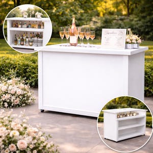 May include: A white bar with a countertop, featuring a bottle of champagne, champagne flutes, and a sign that reads "Signatures". The bar has a lower shelf with bottles and glasses. The bar is set up outdoors with floral arrangements.