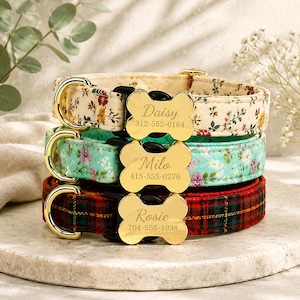 May include: Three pet collars with gold-toned D-rings and bone-shaped metal tags. The top collar is cream with floral patterns, labeled Daisy 312-555-0184. The middle is teal with floral patterns, labeled Milo 415-555-0276. The bottom is red plaid, labeled Rosie 704-555-1938.
