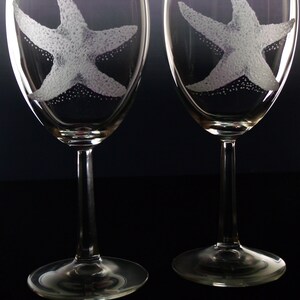 Peut inclure: Deux verres &agrave; vin en verre transparent avec des motifs d'&eacute;toiles de mer grav&eacute;s. Les verres ont un long pied et une base ronde.