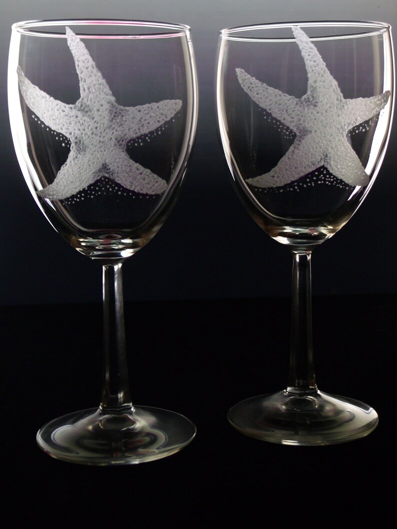 Peut inclure: Deux verres &agrave; vin en verre transparent avec des motifs d'&eacute;toiles de mer grav&eacute;s. Les verres ont un long pied et une base ronde.