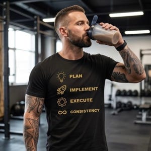 May include: A black short-sleeved t-shirt featuring gold-colored graphics and text. The design includes a lightbulb icon with the word PLAN, a rocket icon with IMPLEMENT, a gear icon with EXECUTE, and an infinity symbol with the word CONSISTENCY.