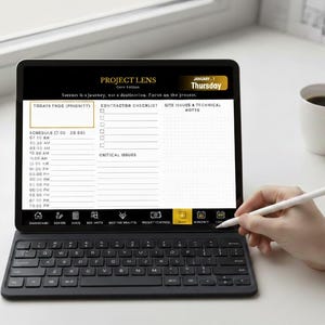 May include: A black tablet with a keyboard and stylus displays a daily planner with the text "PROJECT LENS" and "Thursday, January 1." A white coffee mug sits to the right. The tablet's screen shows a schedule and checklist.
