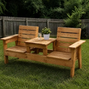 May include: A light brown wooden outdoor bench featuring two slatted seats separated by a central square table. The bench has flat armrests on each end. A small white pot containing a green plant and a clear glass of water sit on the table.